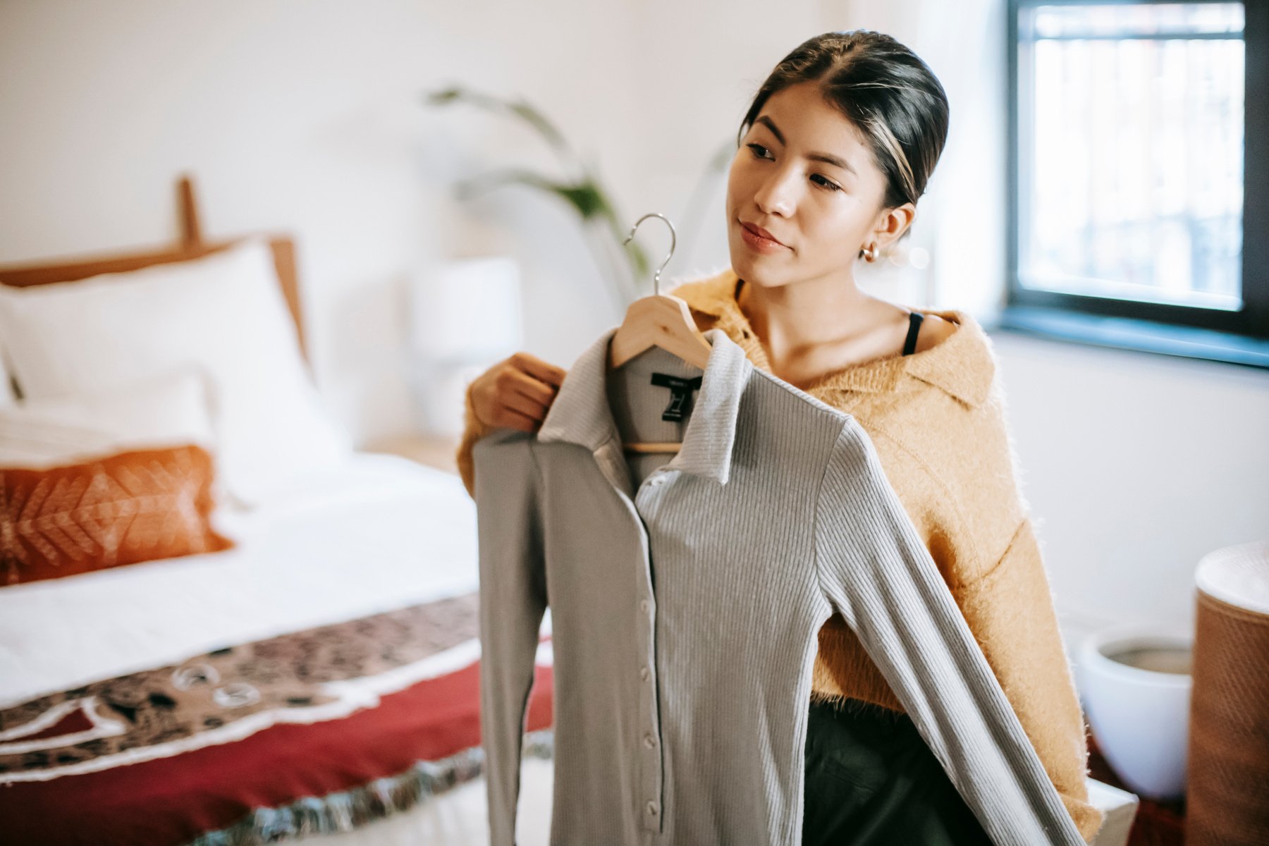 Asian woman trying on clothes in bedroom